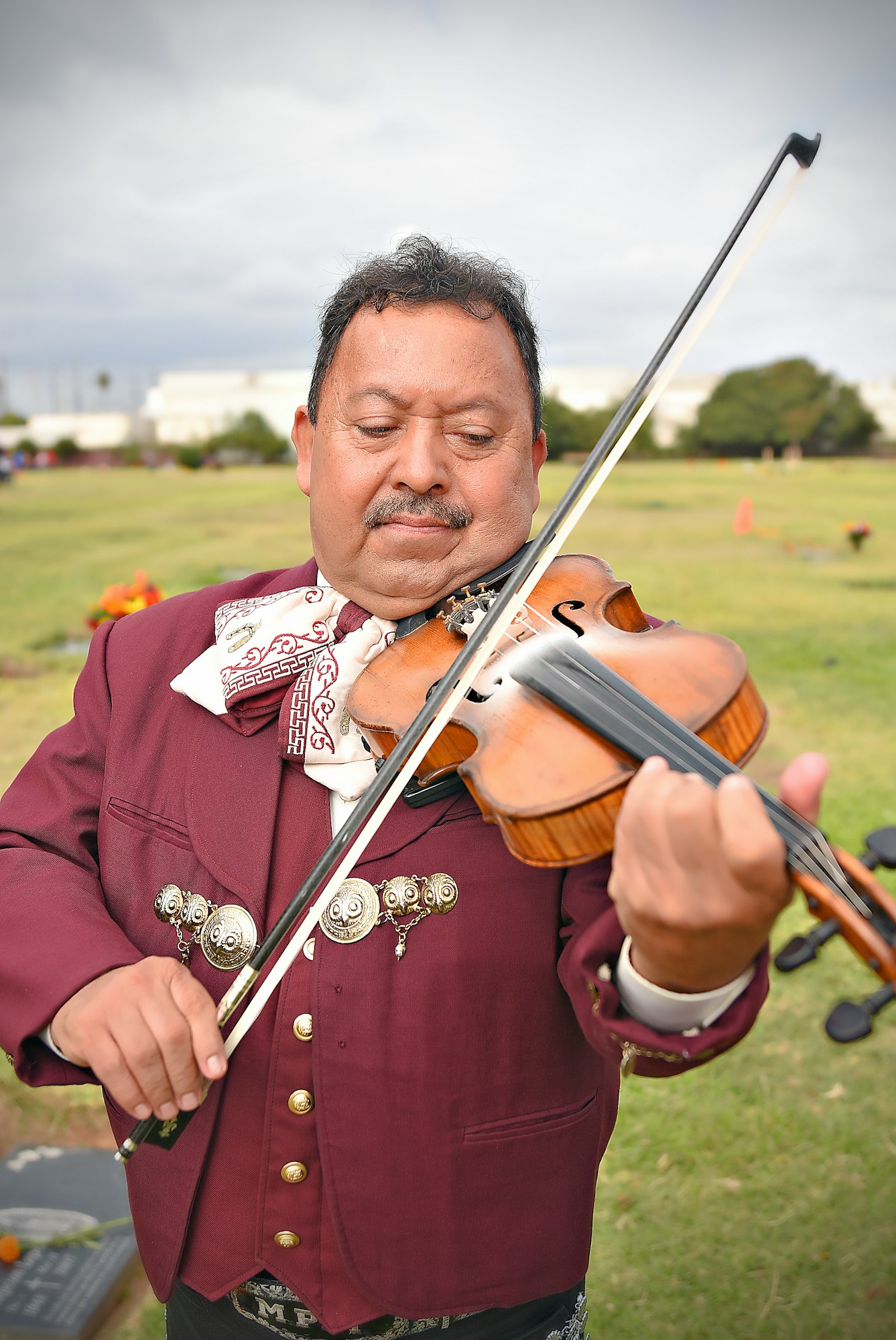 A man in traditional attire playing the violin outdoors.