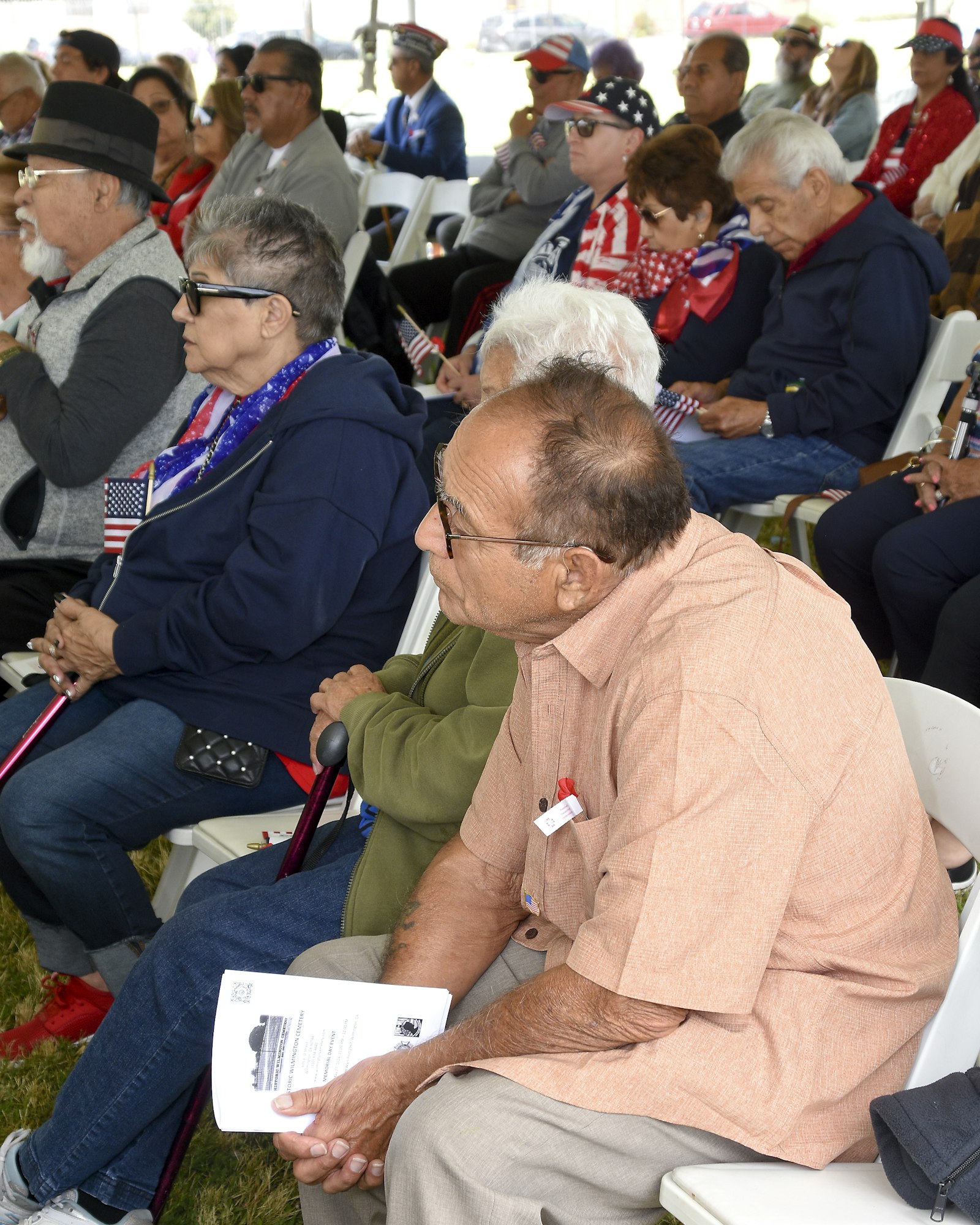 An audience seated at an event, some wearing patriotic accessories.