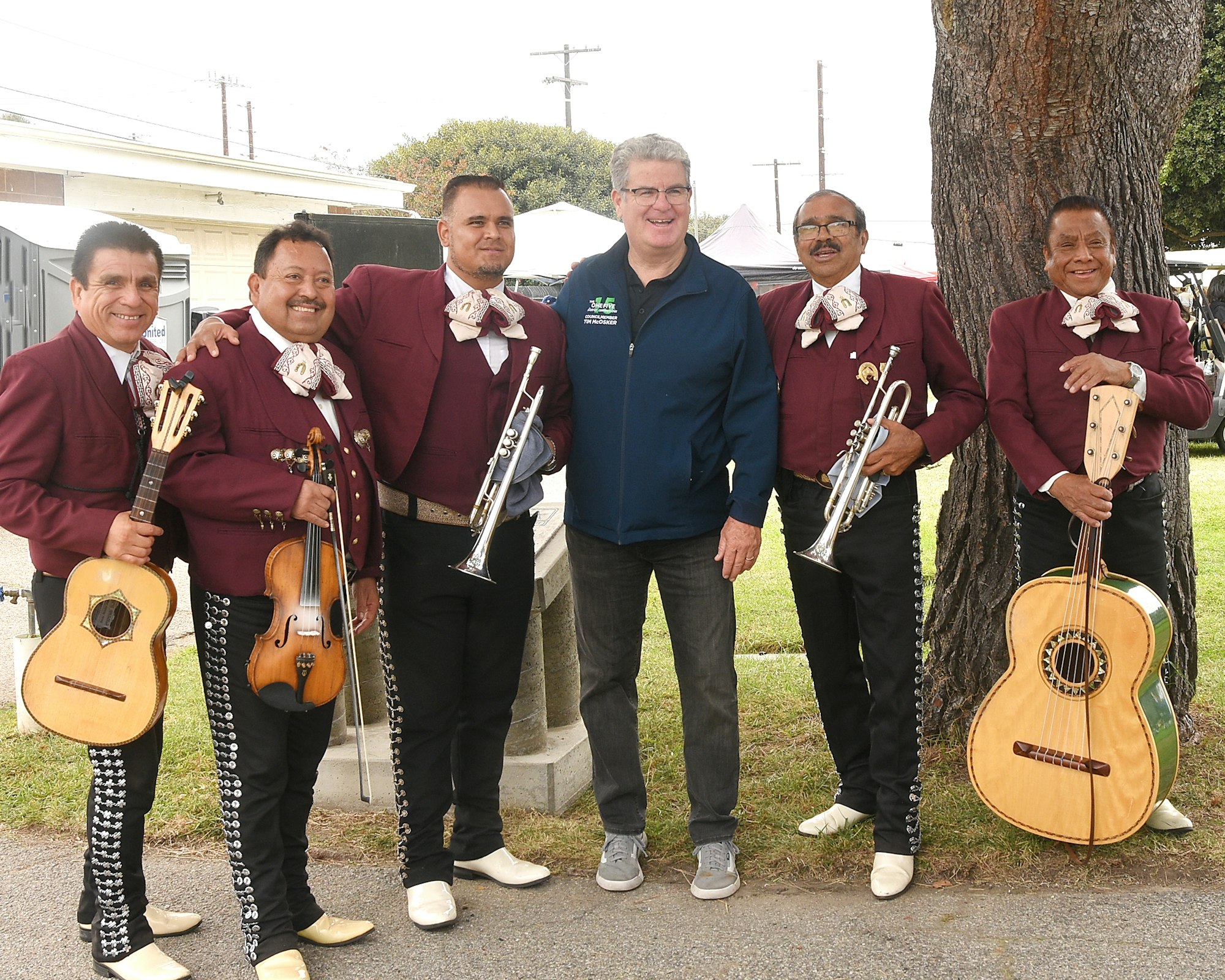 A group of mariachi musicians with instruments posing with a man.