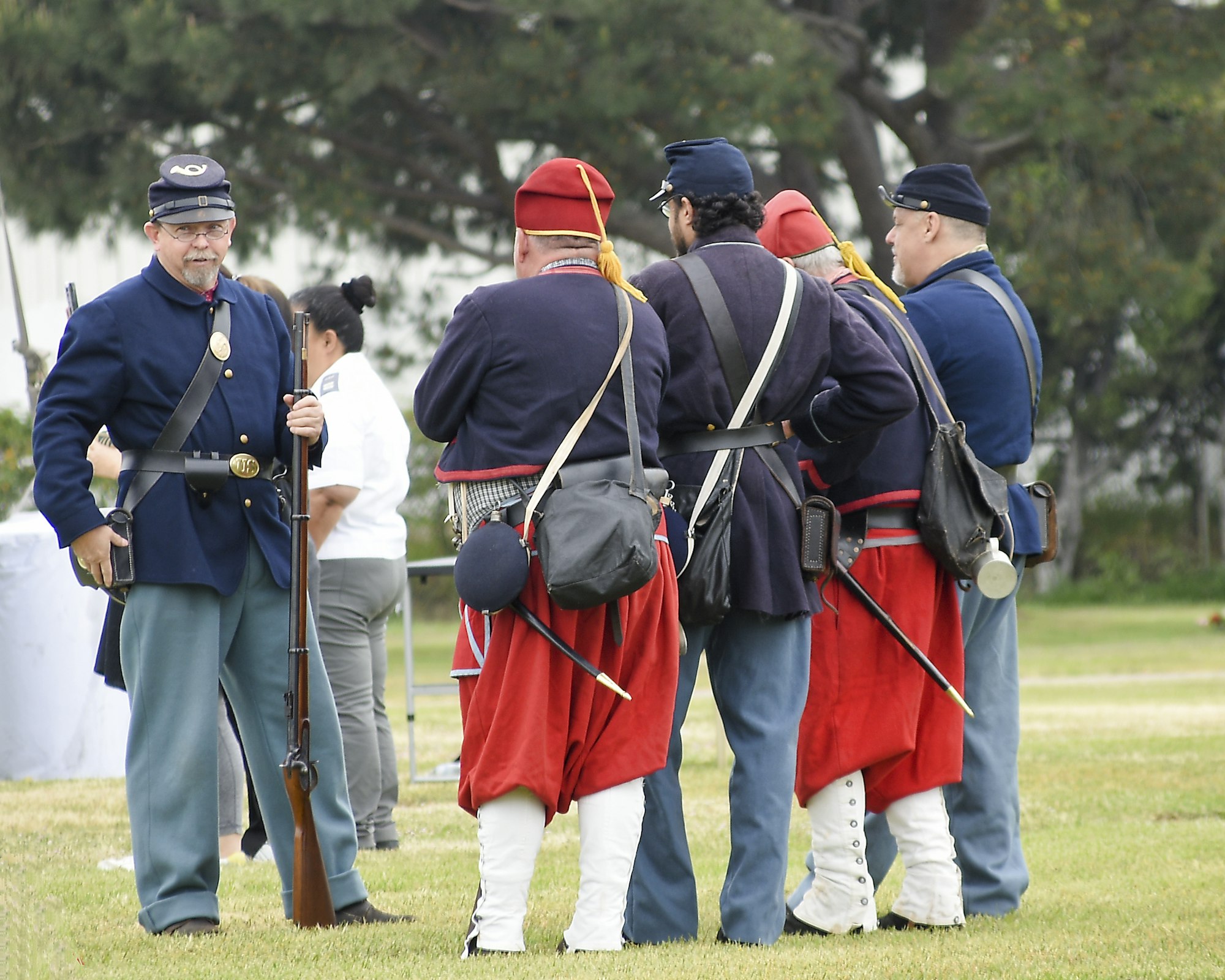 People in historical military uniforms with rifles, possibly reenactors.