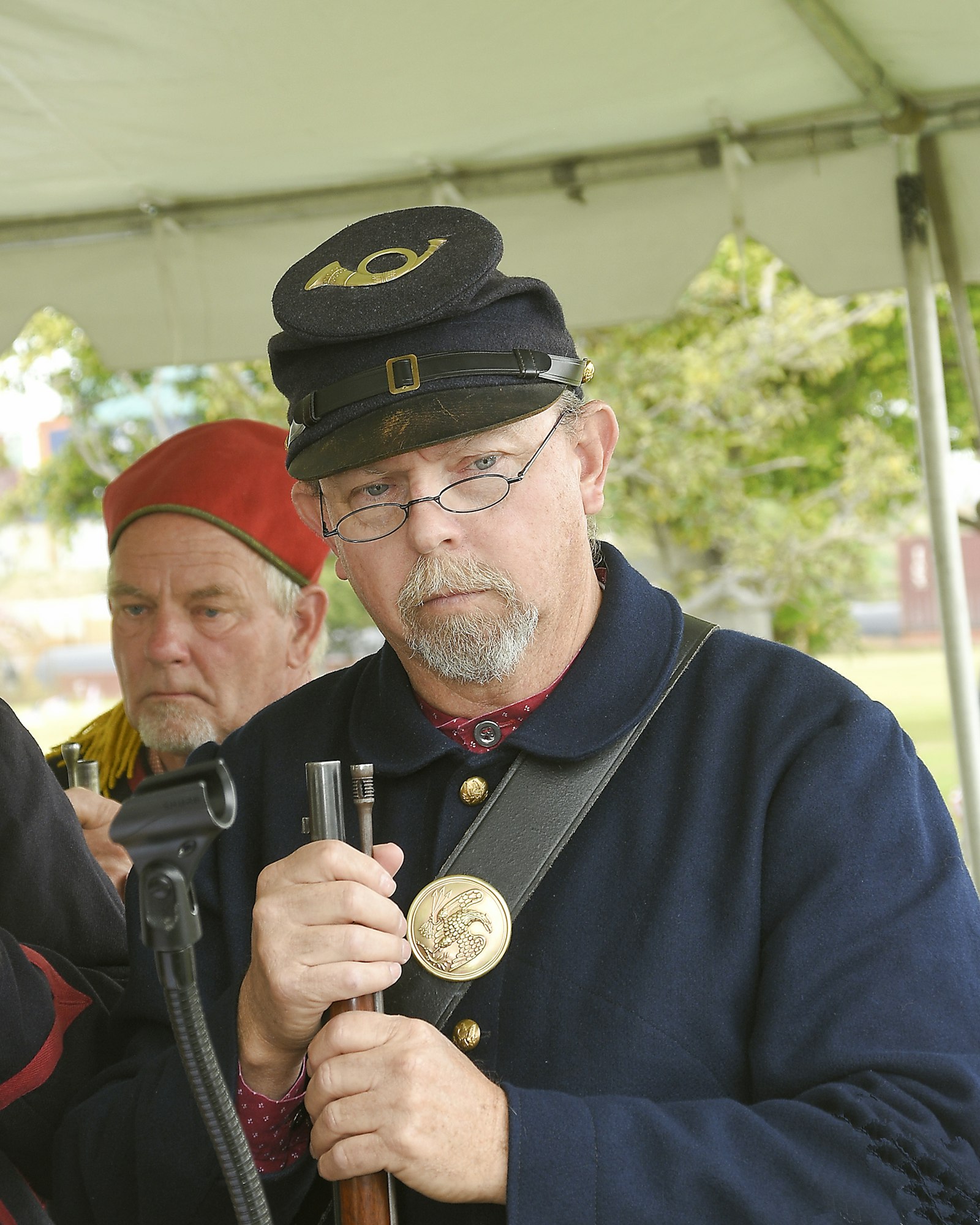 A man in Civil War-era Union uniform with another reenactor blurred in the background.
