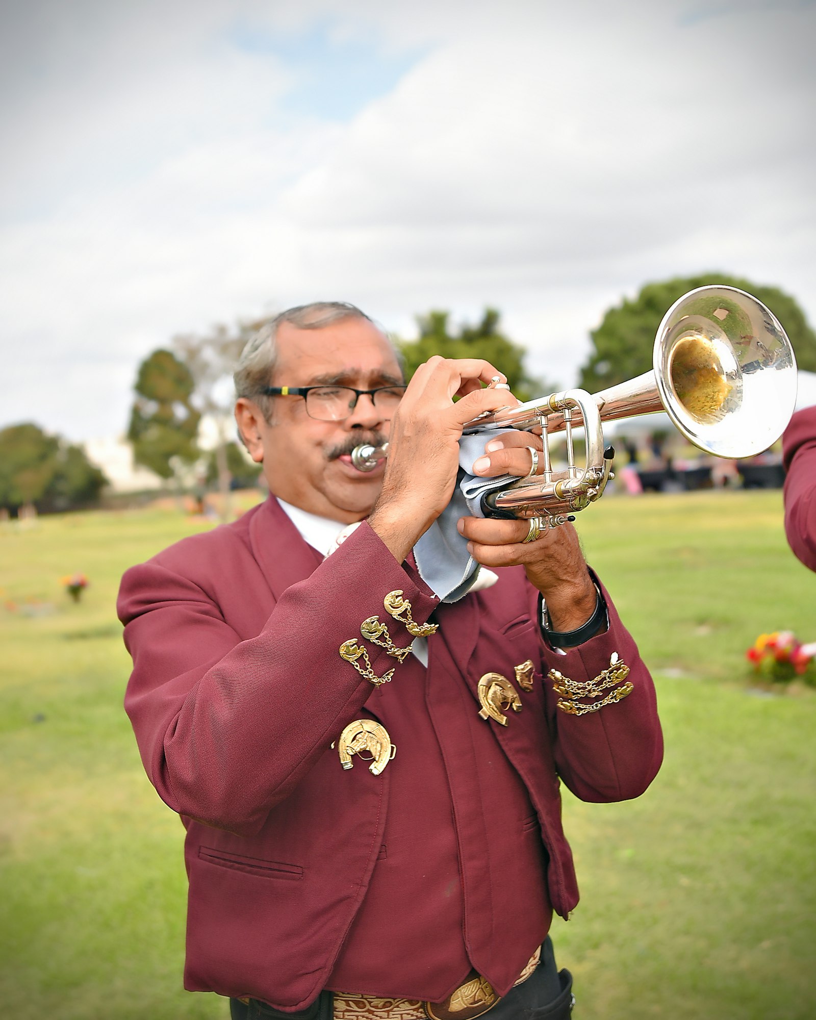 A person playing a trumpet outdoors with visible breath condensation.