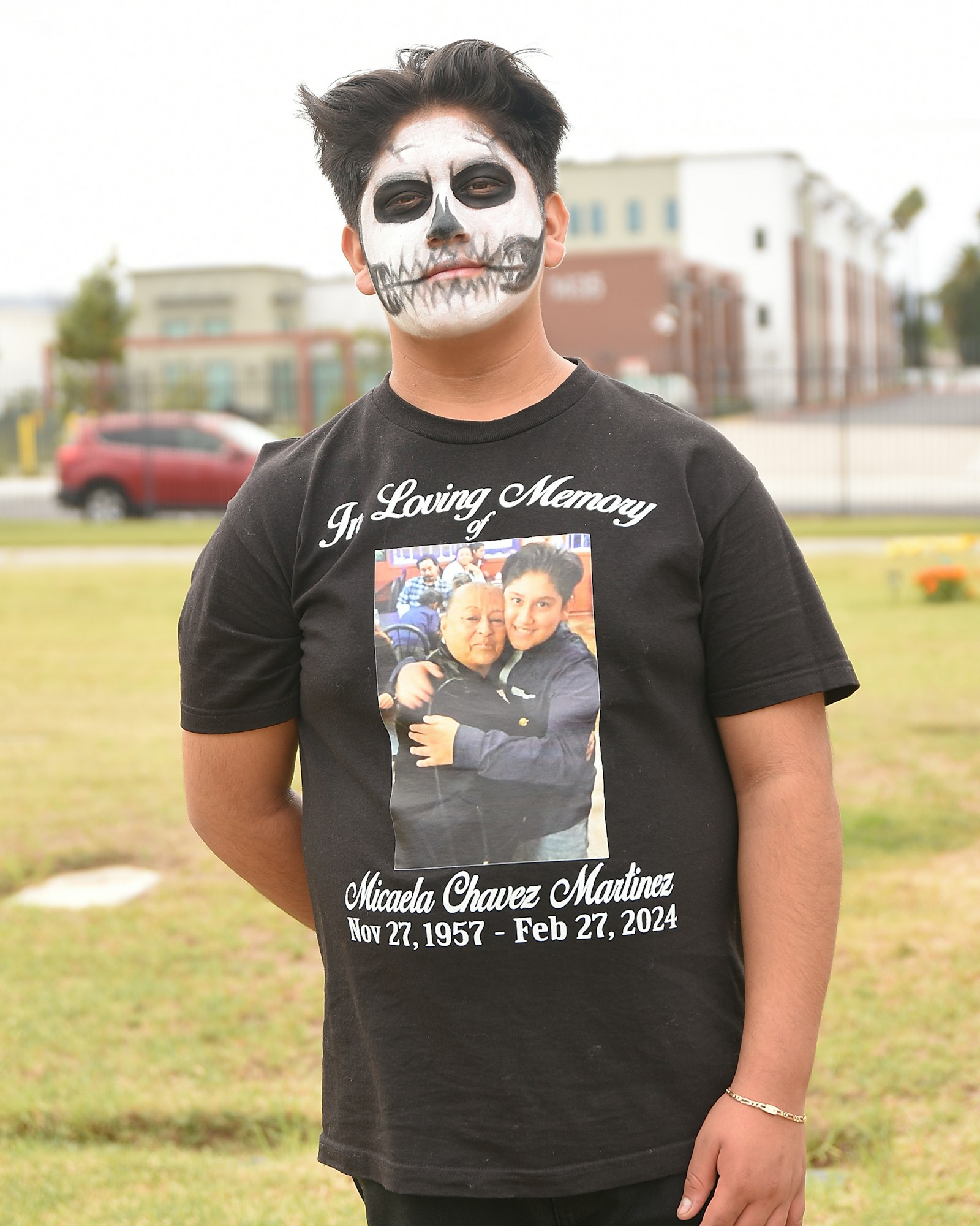 Person with skull face paint wearing a memorial T-shirt.
