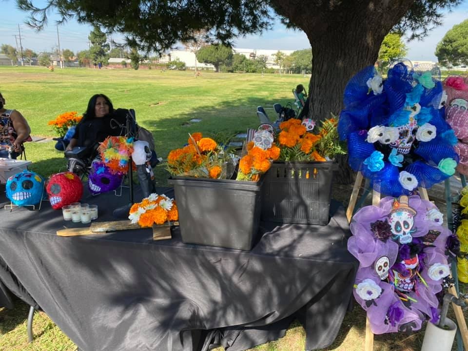 A table with colorful decorations, including flowers, skulls, and candles, set up outdoors, likely for a celebration or event.