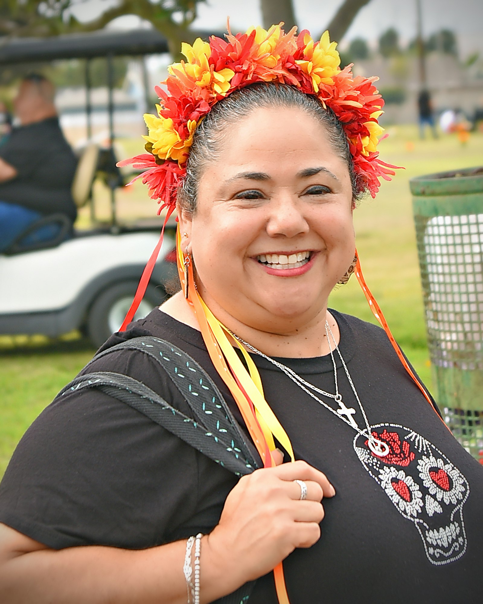 A smiling person with a floral headband and a skull design on her shirt.