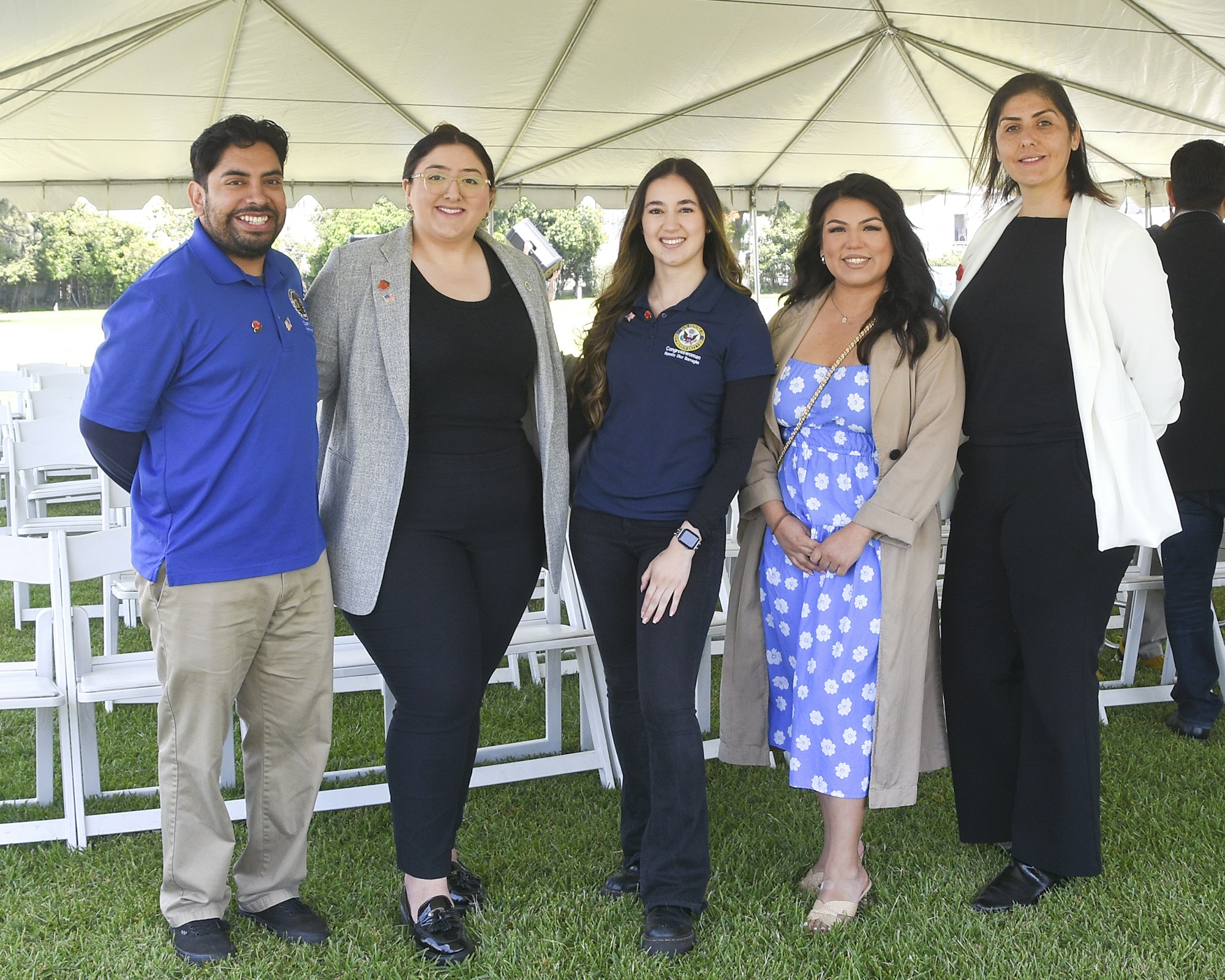 Group of five people posing together outdoors, likely at a professional or social event, smiling for the camera.