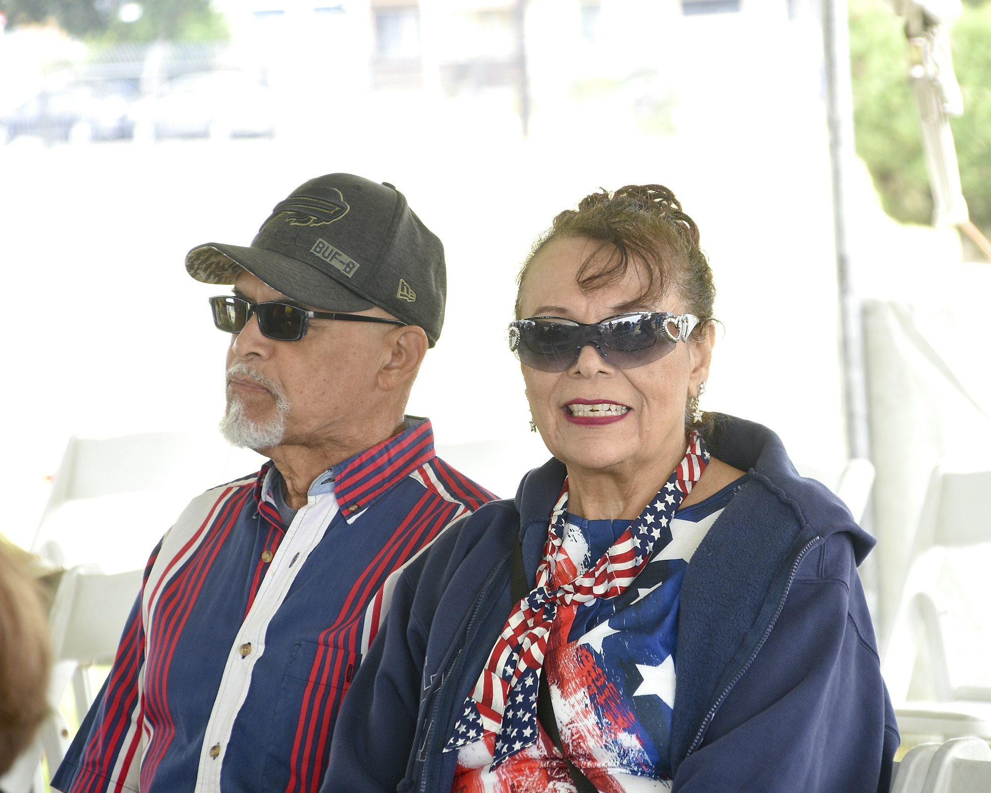 Two people wearing sunglasses and patriotic-themed clothes.