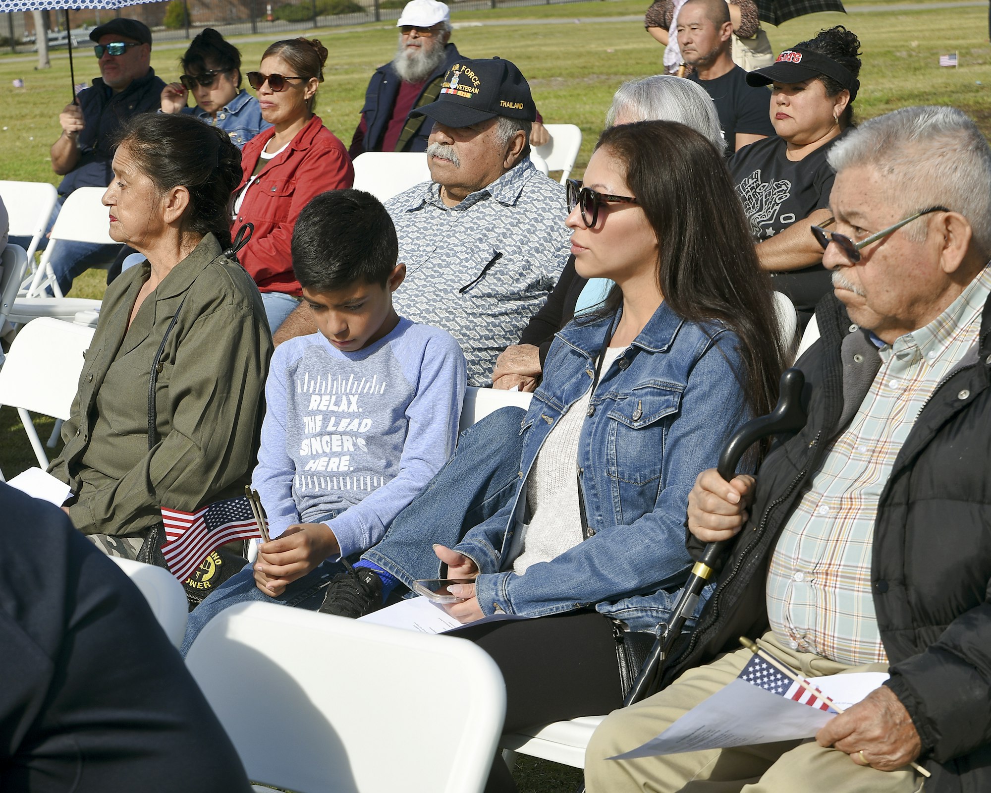 May contain: people, person, woman, adult, female, baseball cap, hat, cap, clothing, child, boy, male, man, glasses, accessories, crowd, shoe, footwear, chair, and furniture