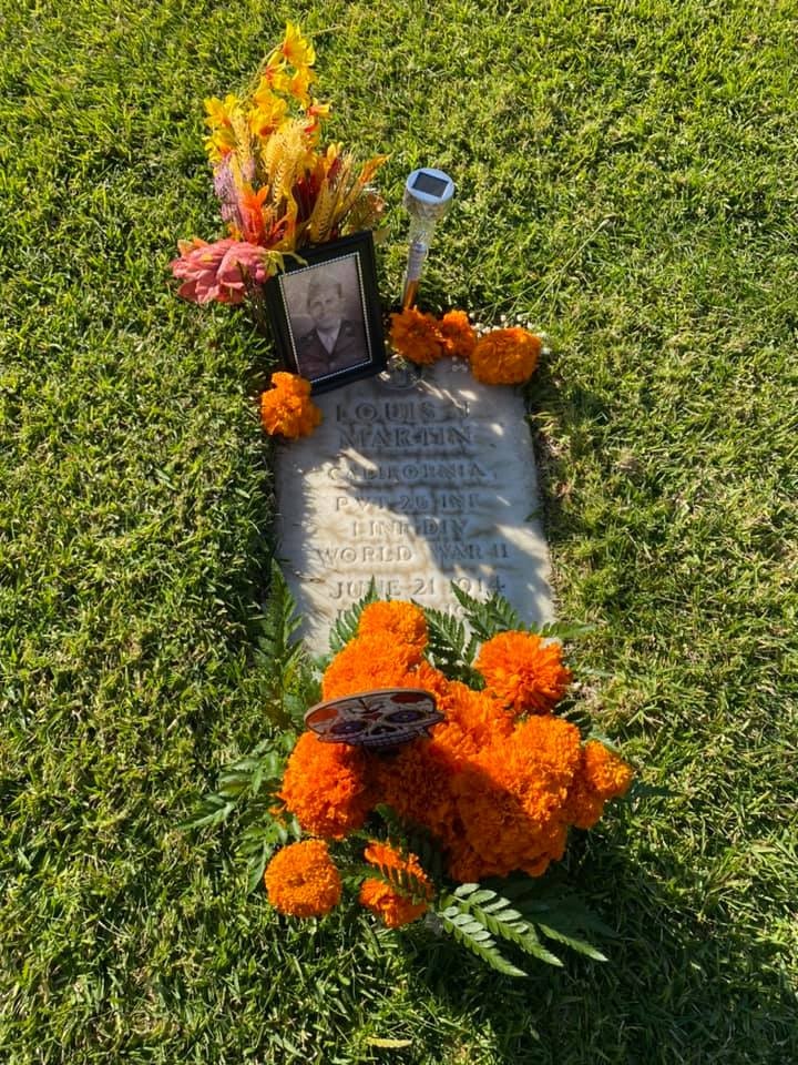 The image shows a gravestone adorned with flowers, a photo, and a memorial for a World War II veteran named Louis Martin.