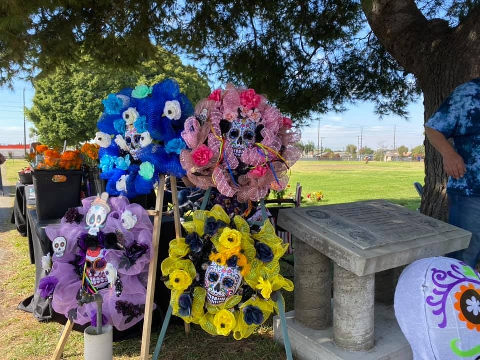 The image features colorful decorative wreaths inspired by Día de los Muertos, adorned with sugar skull motifs and flowers.