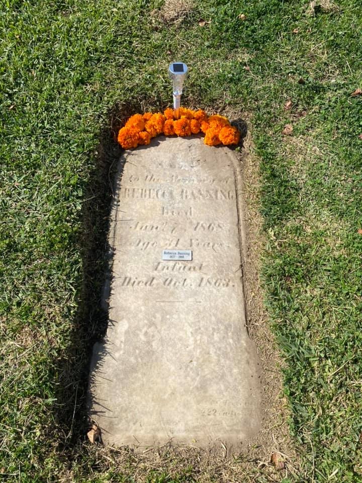 The image shows a grave marker with flowers, indicating a burial for someone named Rebecca Bassano, who died in 1863.