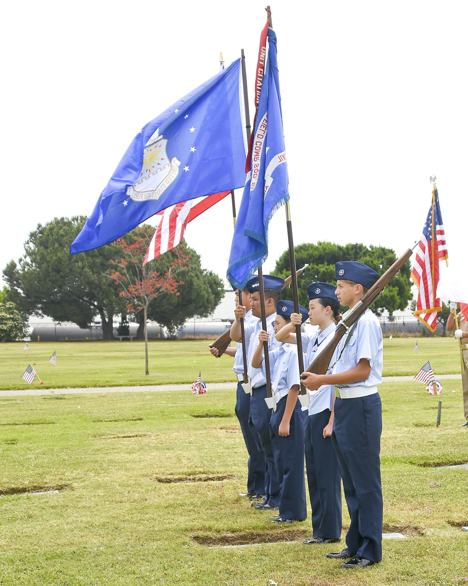 A group of individuals in uniform holding flags and rifles at a ceremonial event.