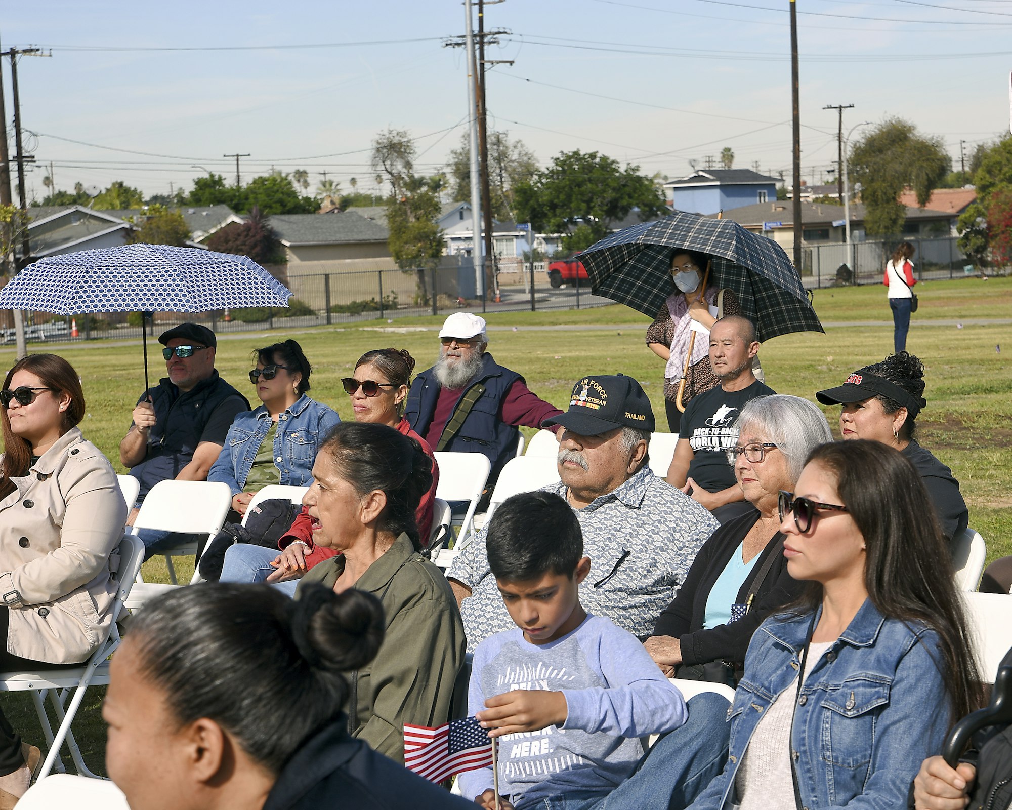 May contain: woman, adult, female, person, shelter, outdoors, building, architecture, baseball cap, hat, cap, clothing, people, man, male, handbag, bag, accessories, sunglasses, flag, glasses, shoe, footwear, and crowd