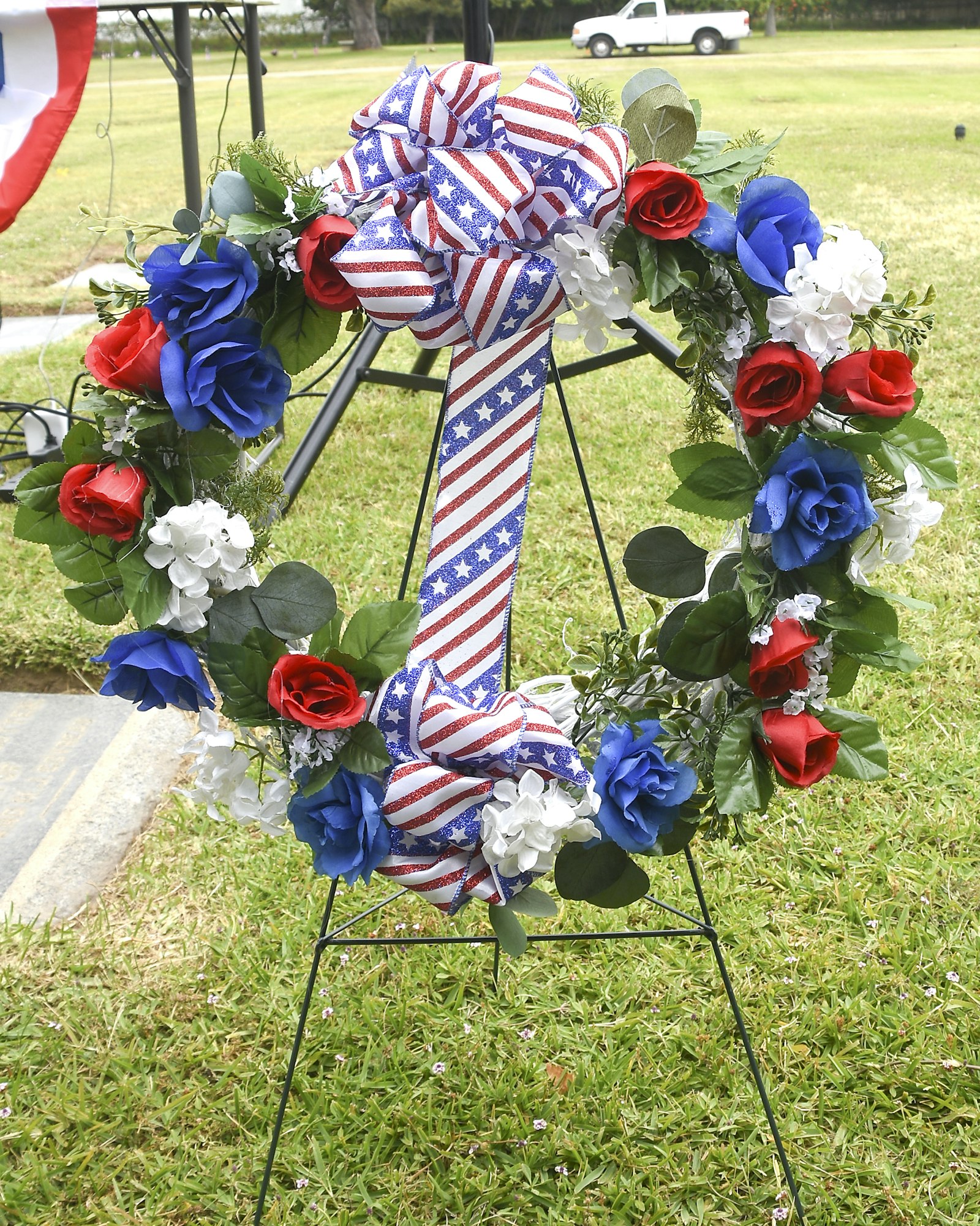 A wreath with an American flag ribbon and red, white, and blue flowers, possibly for a memorial or patriotic event.