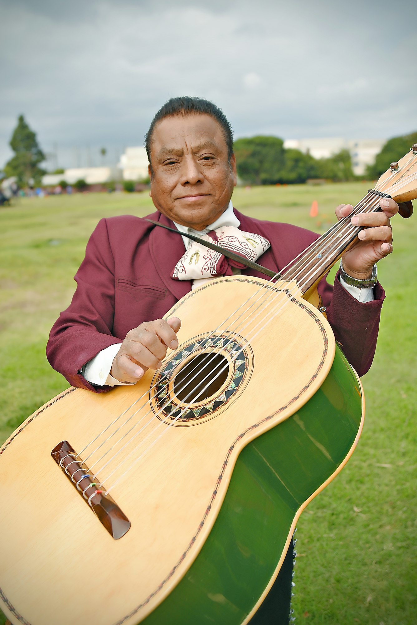 A man in a suit holding a guitar outdoors.