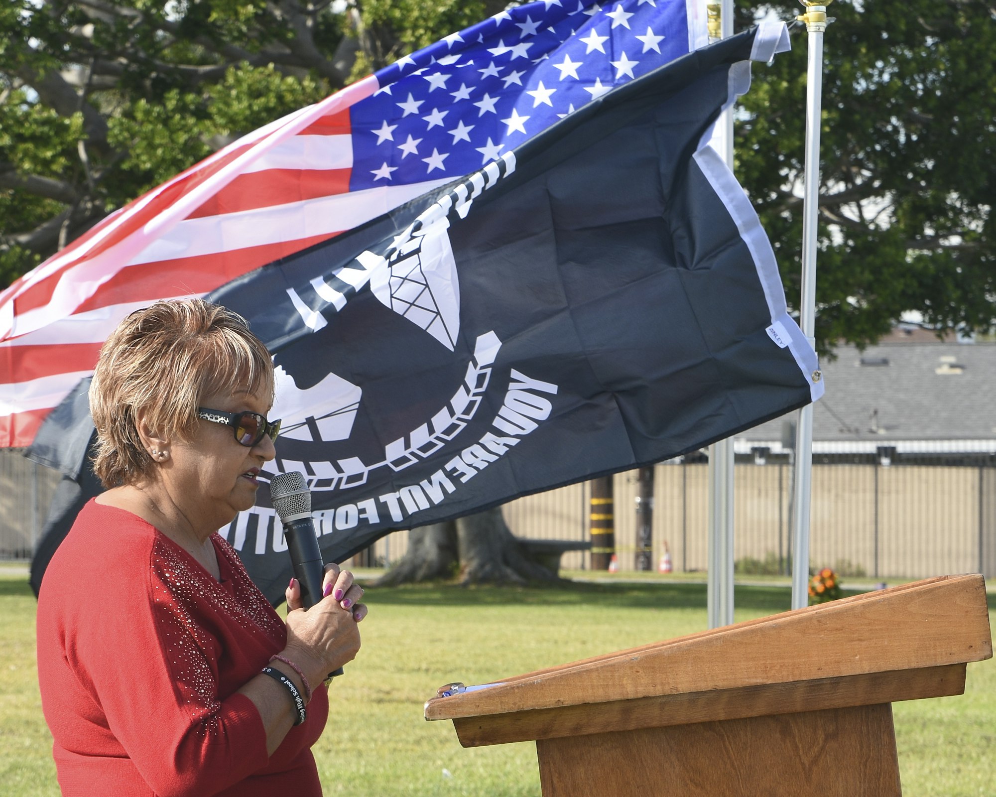 May contain: flag, person, microphone, electrical device, crowd, glasses, accessories, bracelet, and jewelry