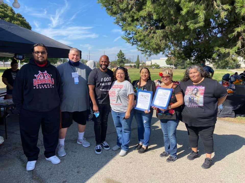A group of people poses outdoors, holding certificates, celebrating an event under a sunny sky.