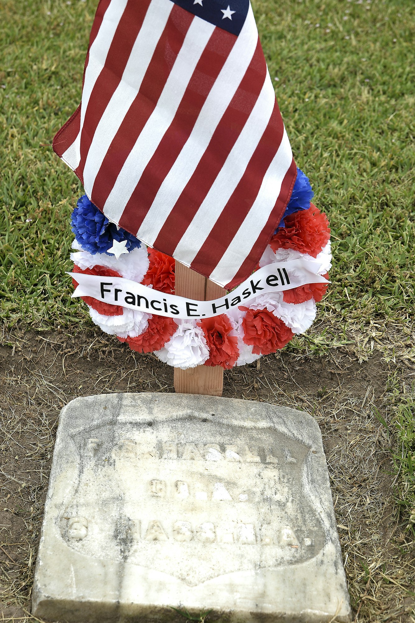 A U.S. flag and wreath on a grave marked "Francis E. Haskell."
