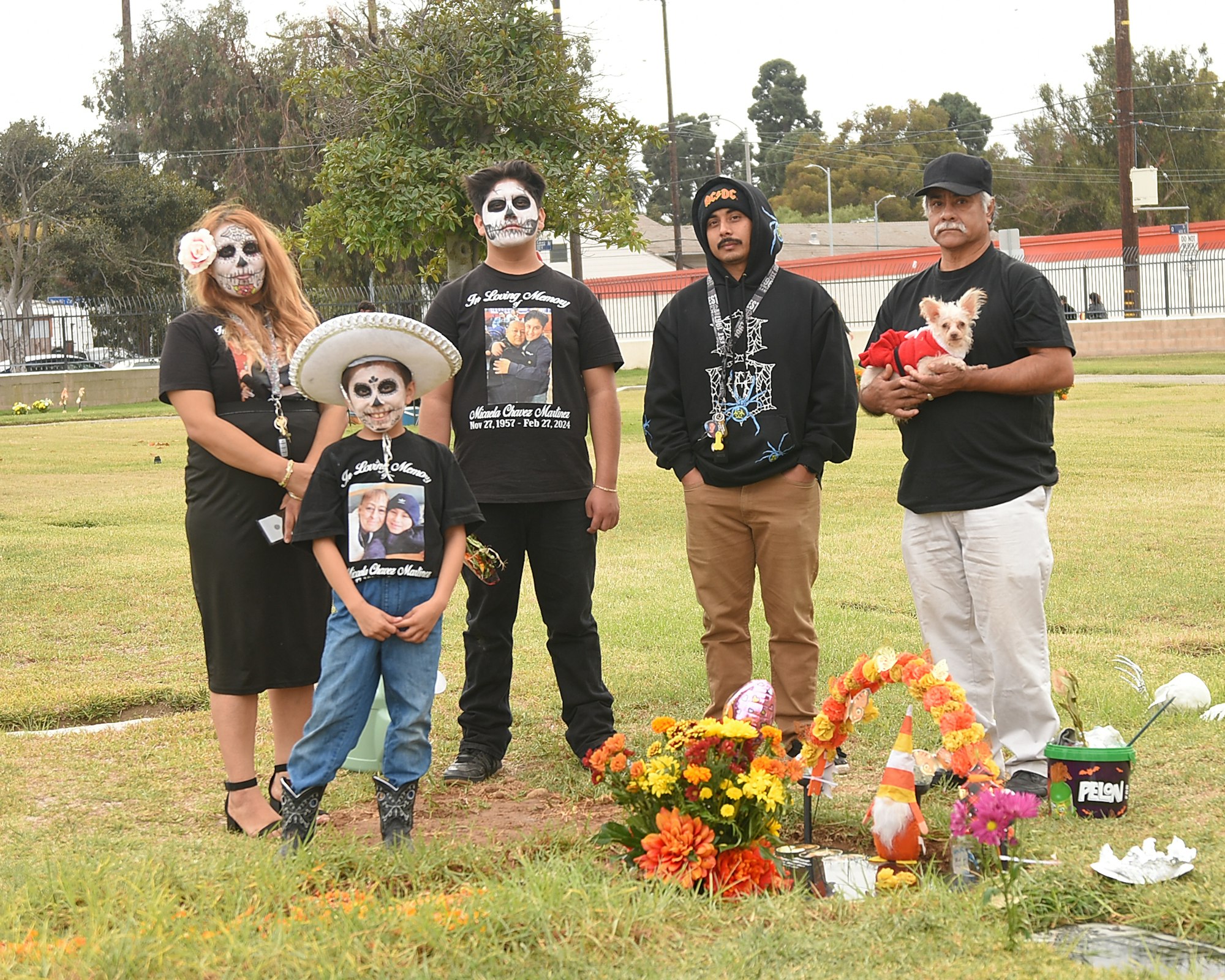 A group with painted faces and a memorial with flowers, suggesting a Day of the Dead celebration.