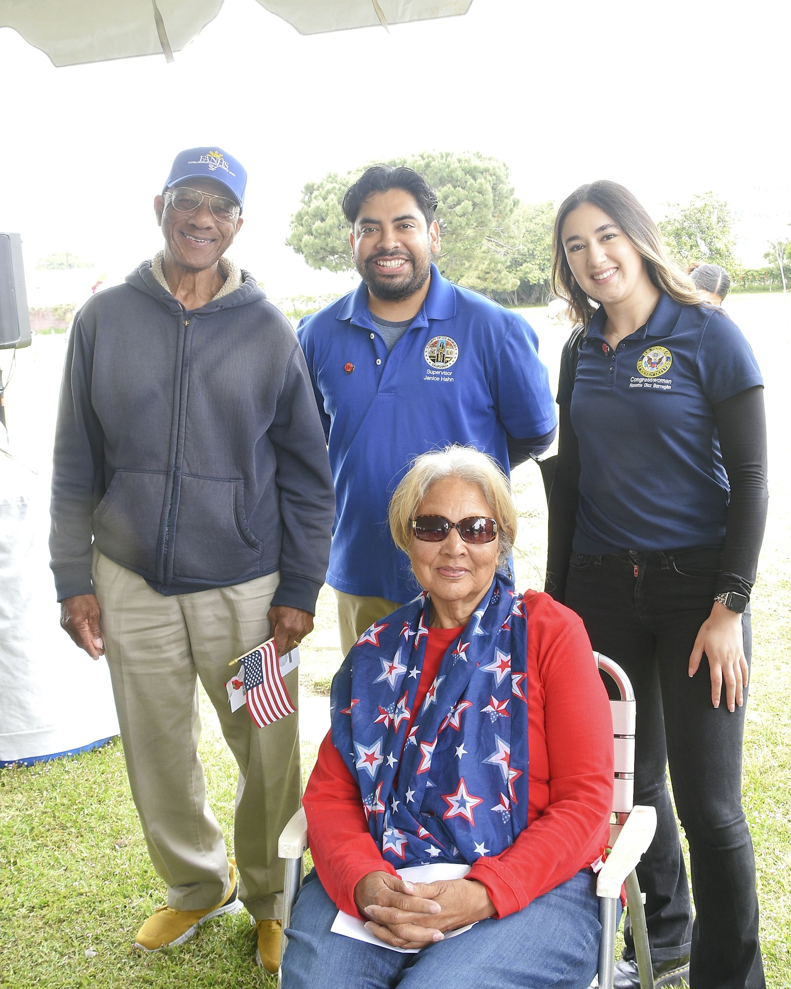 Four people outdoors, wearing patriotic colors, possibly at a civic event.