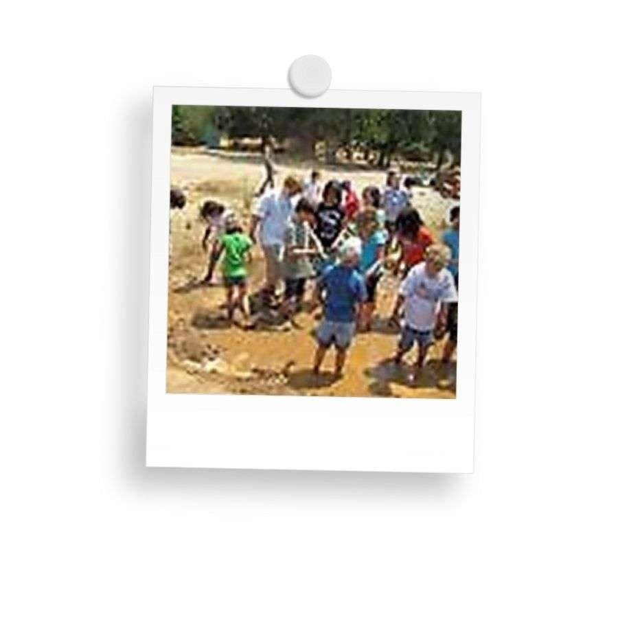 Children playing and digging in a muddy outdoor area.