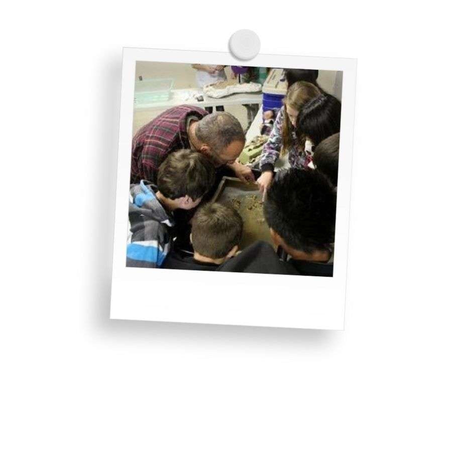 A group of people huddled around, examining something closely on a table.