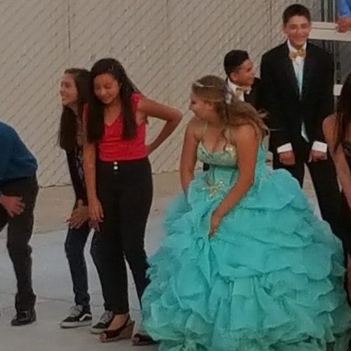A group of young people dressed up, with one in a turquoise ruffled gown.