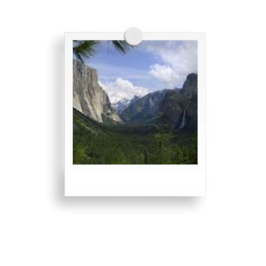 A Polaroid photo showing a valley with towering cliffs, green forest, and waterfalls under a partly cloudy sky.