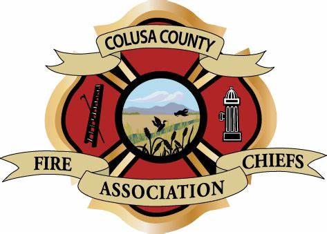 The emblem of the Colusa County Fire Chiefs Association featuring firefighting tools, scenic backdrop, and text.