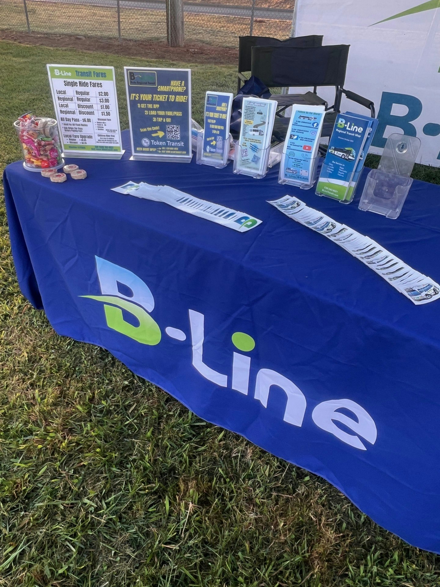 A table displaying B-Line transit fares, brochures, and promotional materials with a blue tablecloth and some candy.