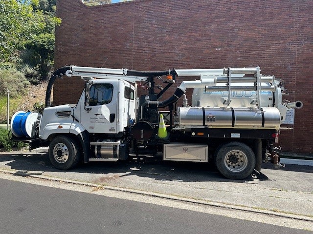 A parked sanitation truck with cleaning and vacuum equipment.