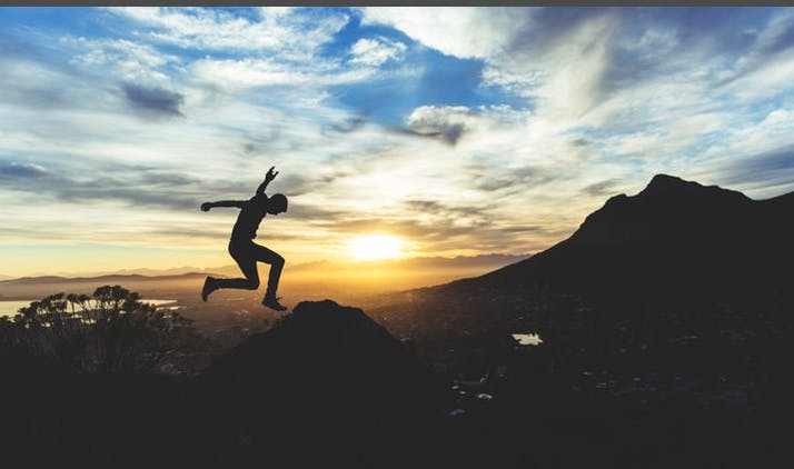 Man jumping in the air against a cloudy blue sky