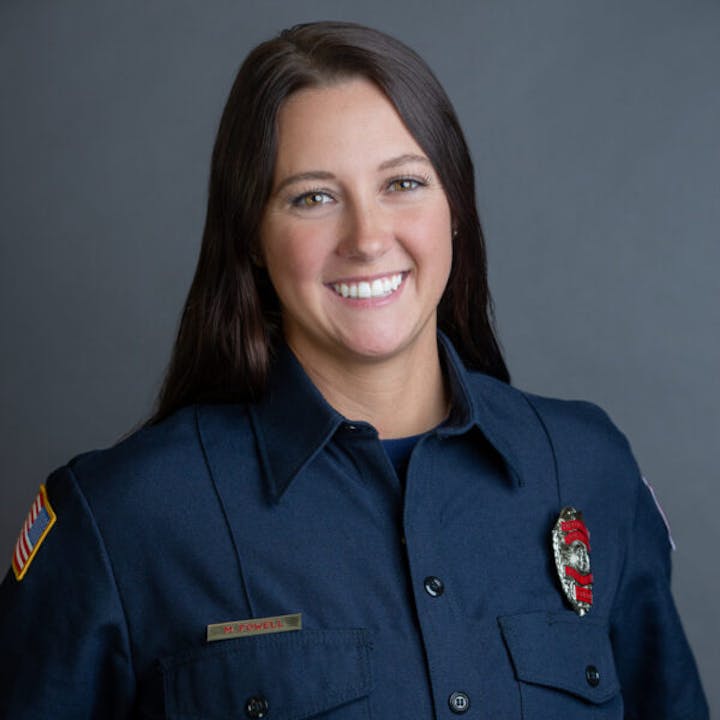 A person in a firefighter uniform smiling at the camera.