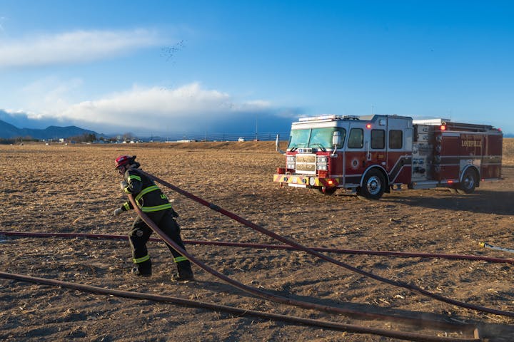May contain: clothing, glove, helmet, person, fire truck, transportation, truck, vehicle, footwear, shoe, boat, and car