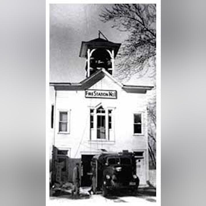 Old fire station with a bell tower and a fire truck parked in front.