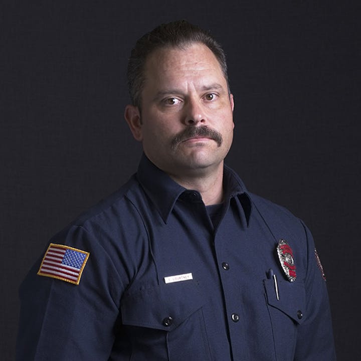 A person in a uniform with an American flag patch and a badge.