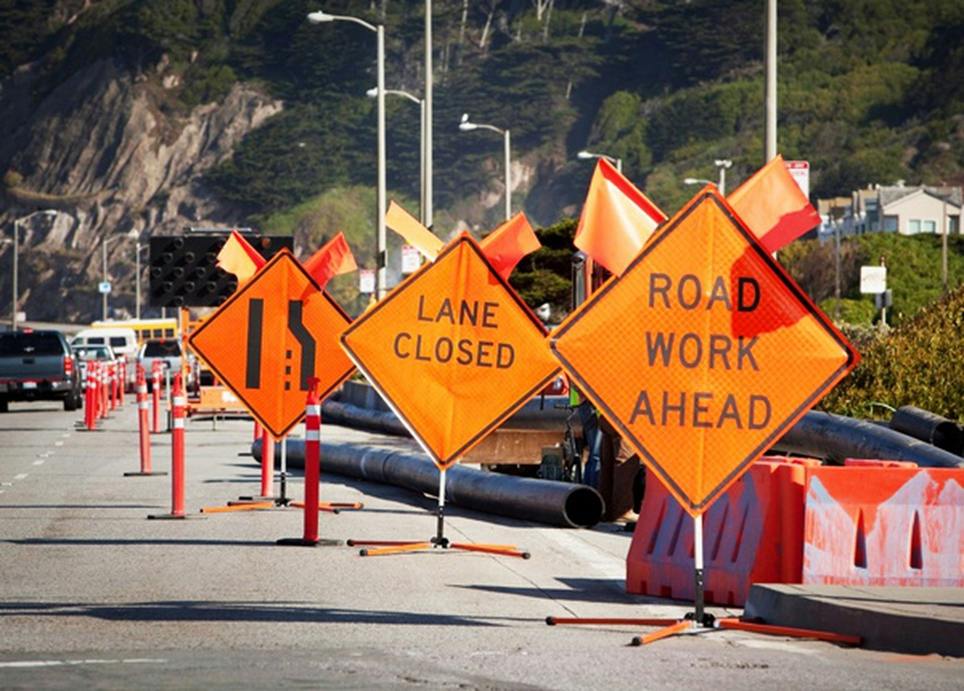 Orange road work signs and cones indicating lane closure.