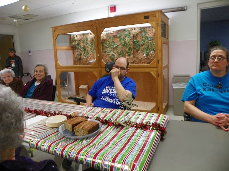 People sitting at tables with a festive tablecloth and some bread on a plate.