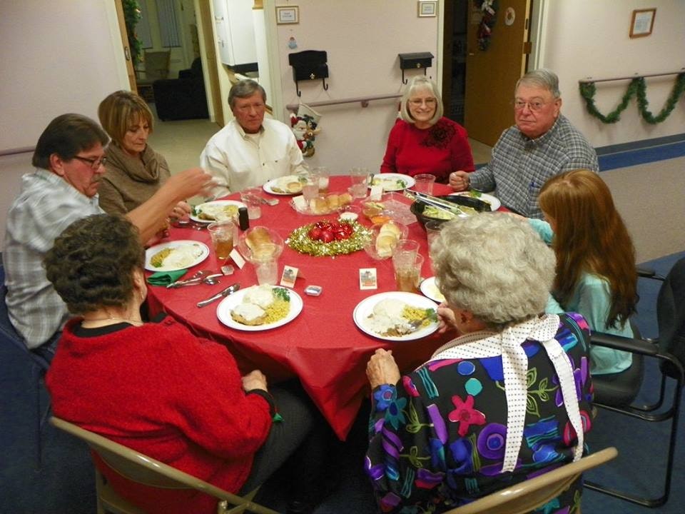 A group of people enjoying a meal together around a festive table with holiday decorations.