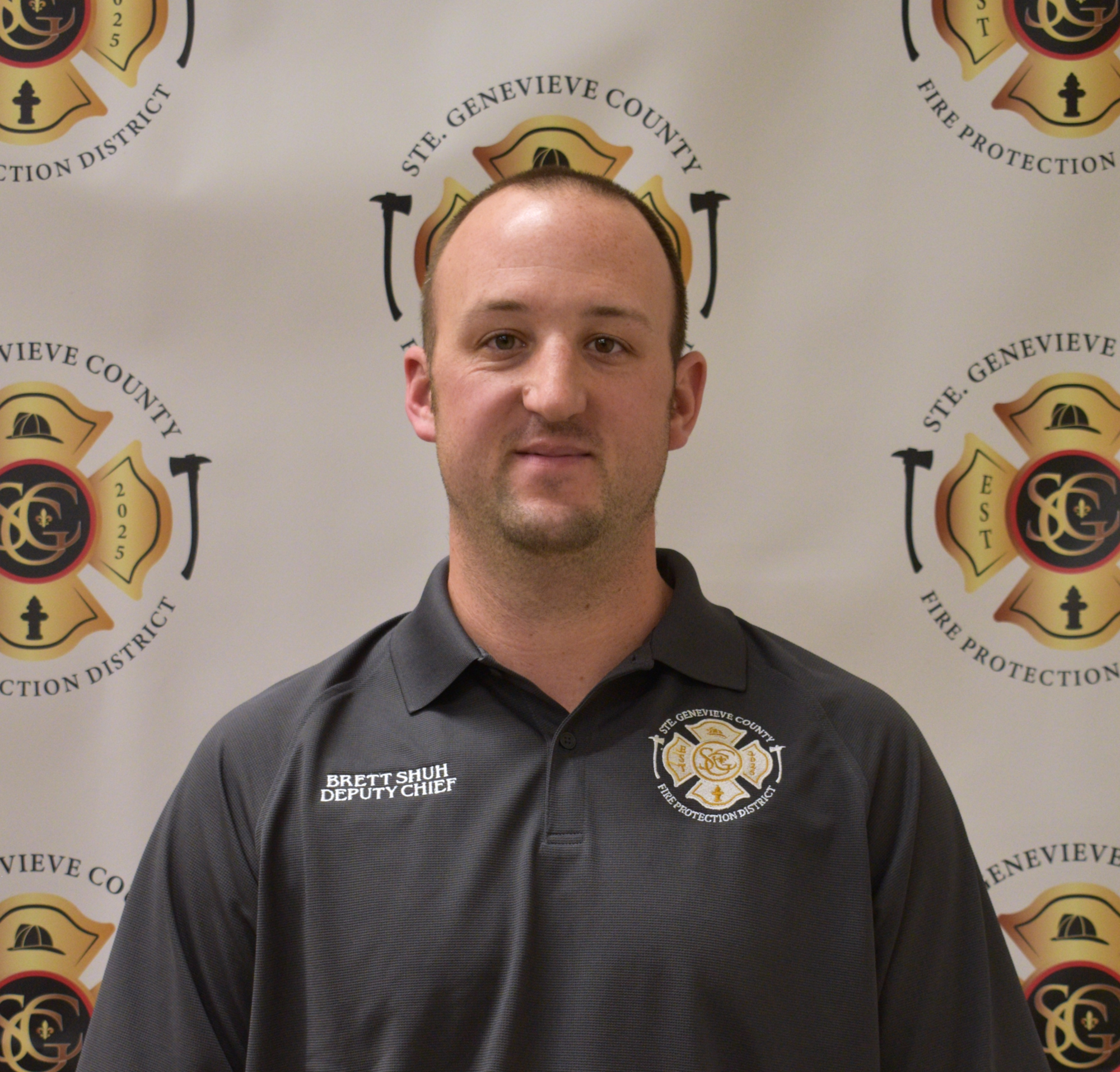 A man in a dark shirt with "Deputy Chief" on it, posing in front of a fire department backdrop.