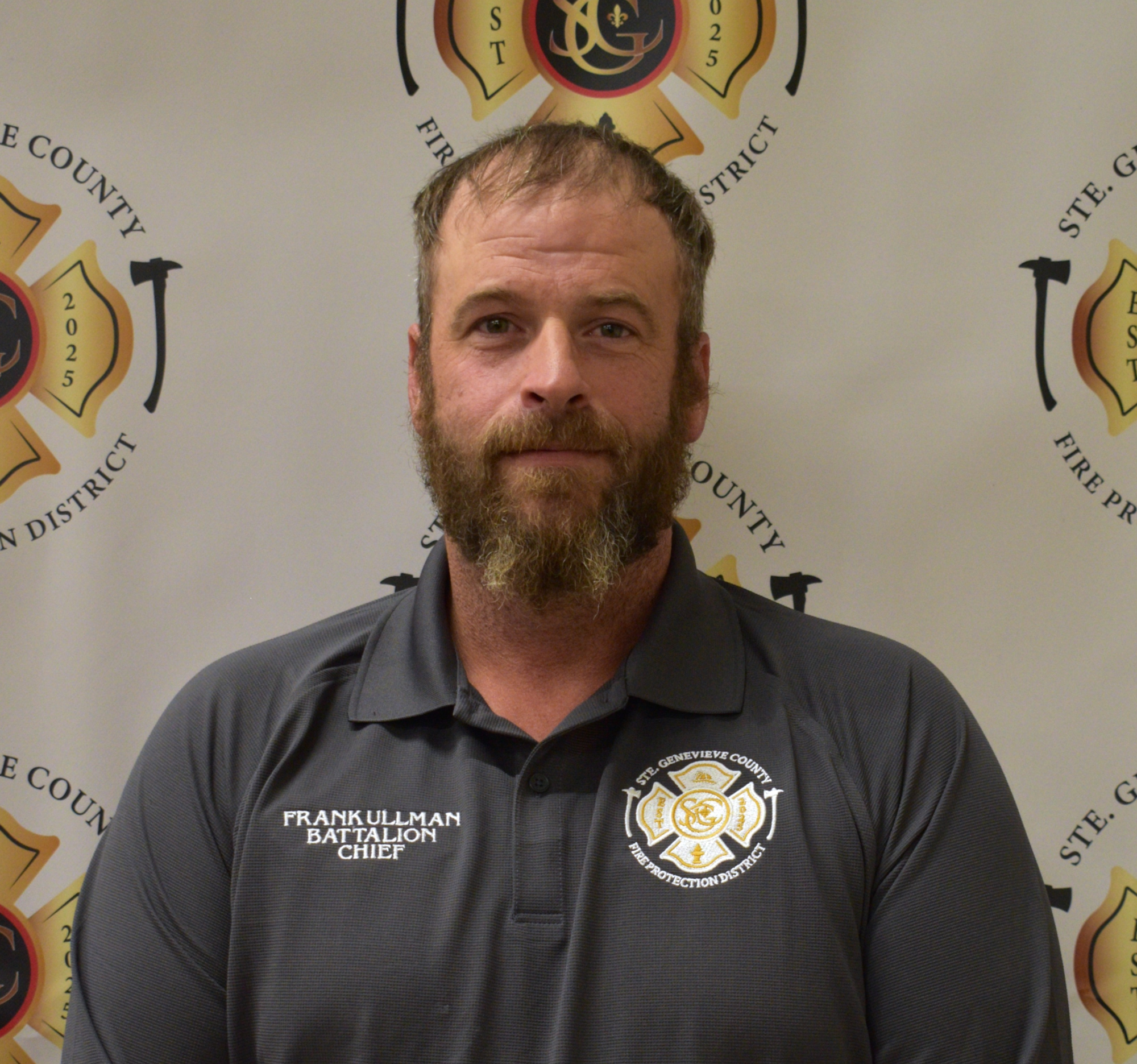 The image features a man in a dark shirt with a fire department logo, standing against a backdrop of a fire district banner.