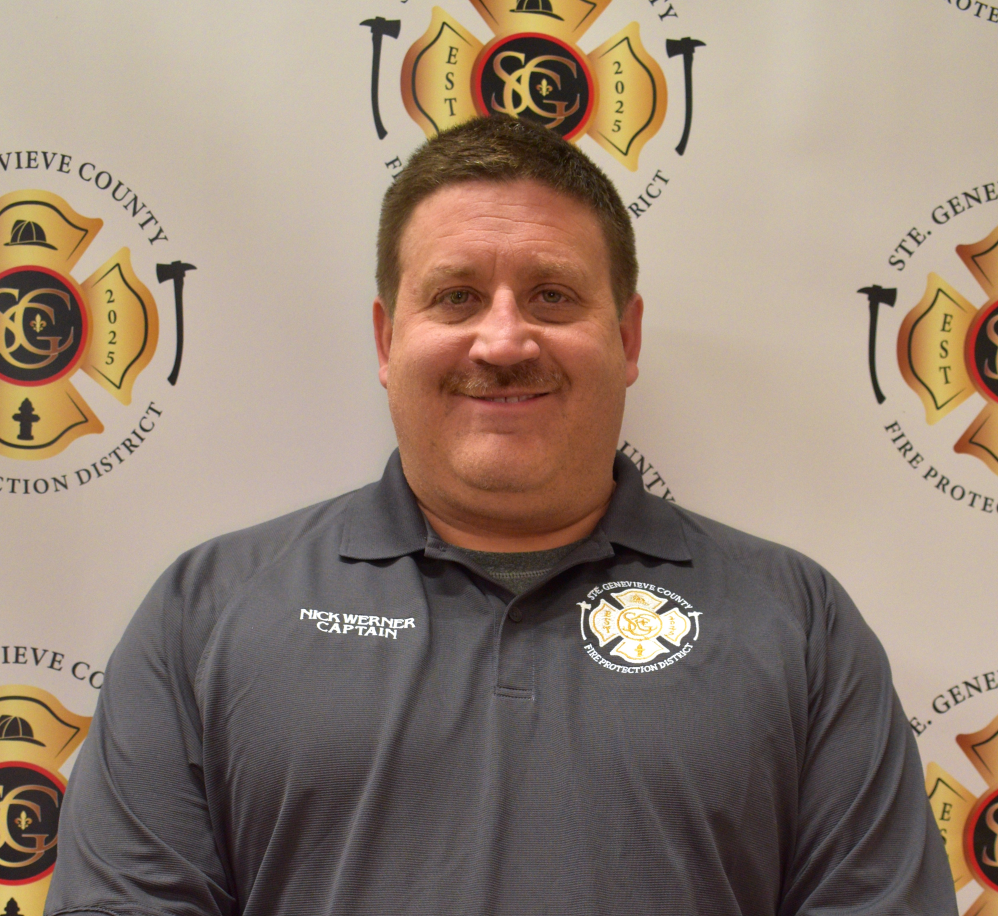 The image features a man in a grey shirt with "Nick Werner Captain" on it, standing in front of a fire protection district backdrop.