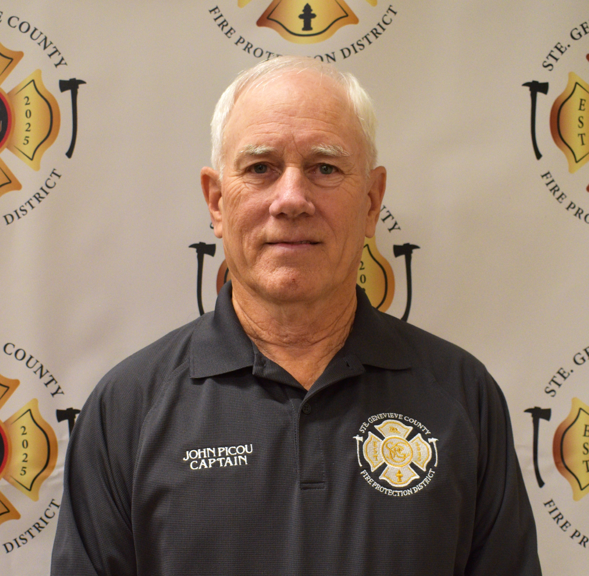 The image features a man in a dark shirt with a fire department logo, standing in front of a backdrop with fire service branding.