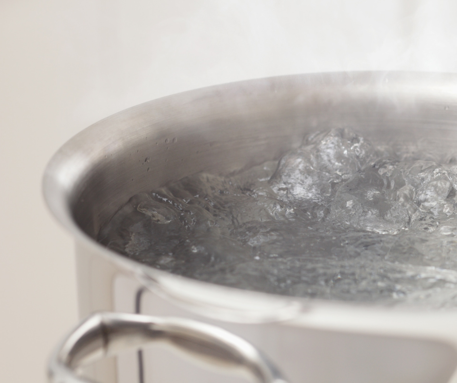A pot with boiling water and steam rising.