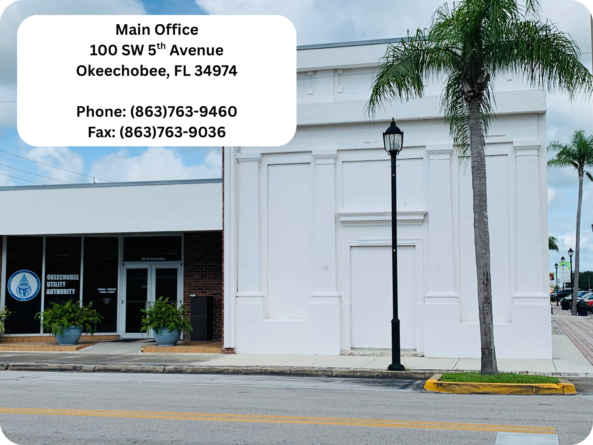Main Office info for Okeechobee Utility Authority on a building exterior with palm trees and a lamppost.