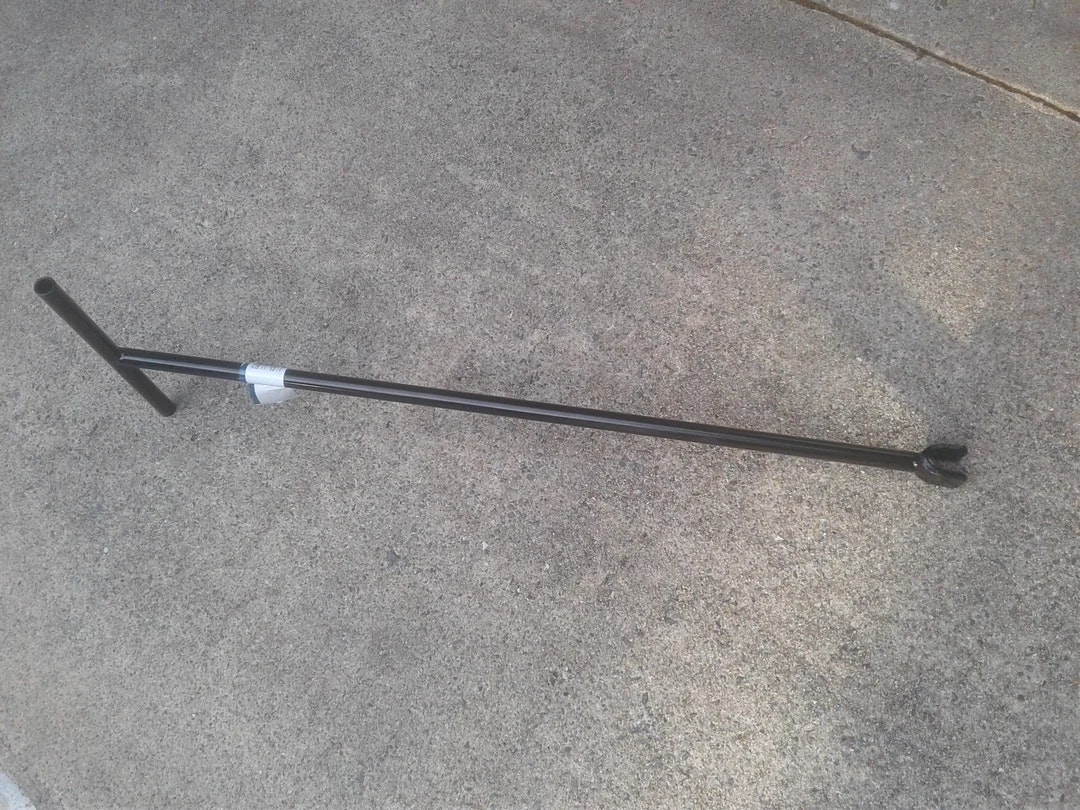 A metal lawn edger is lying on a concrete surface.