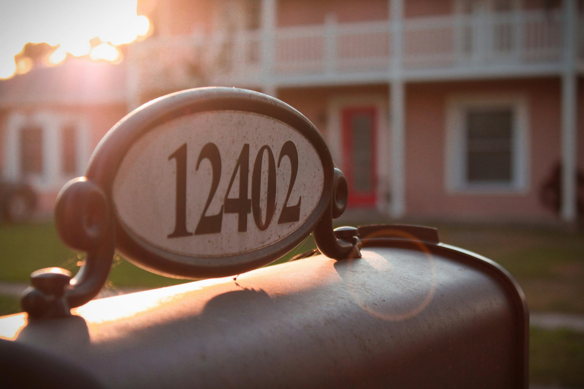 Mailbox with house number "12402" in front of a pink house at sunset.